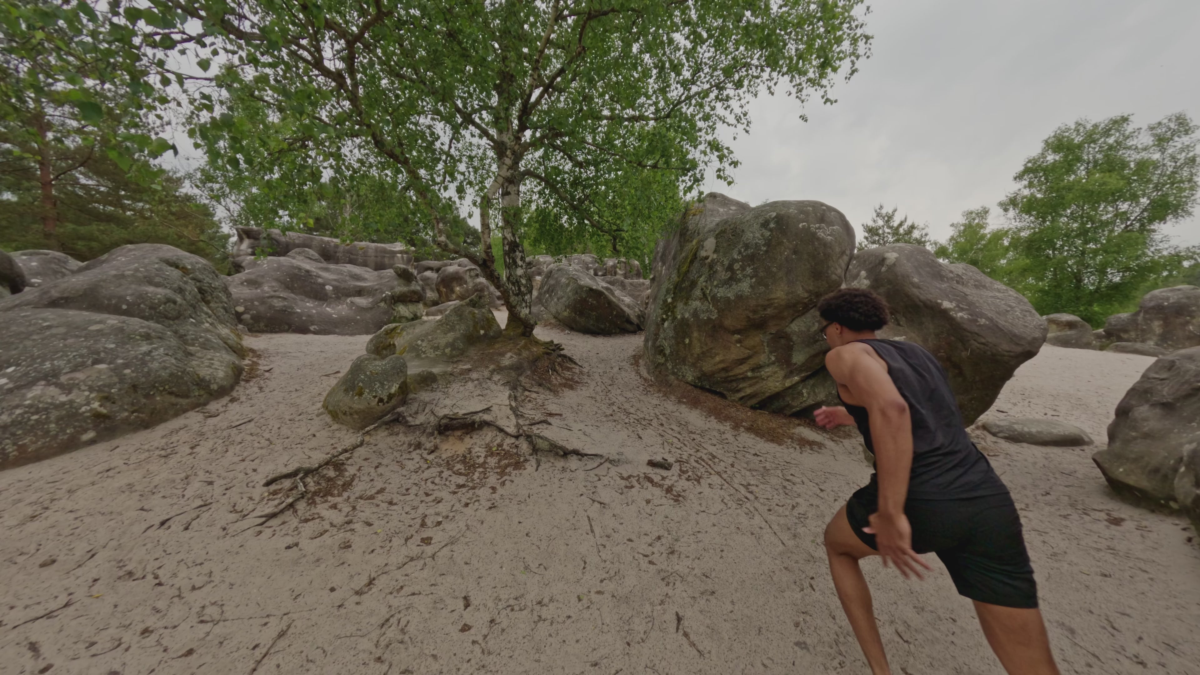 Load video: Man running in sportswear in sand between rocks with a biometric bracelet